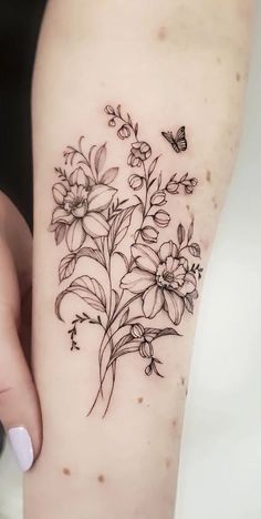 a woman's arm with flowers and a butterfly tattoo on the left side of her leg