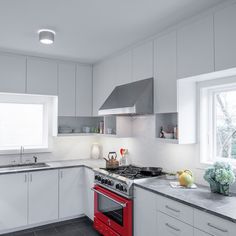 a kitchen with white cabinets and red oven