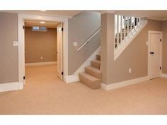 an empty living room with stairs and carpet