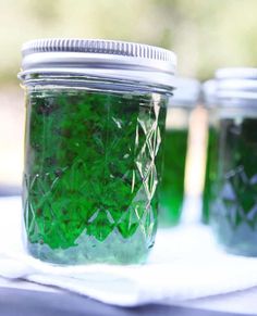 three jars filled with green liquid sitting on top of a table