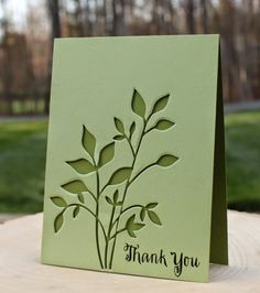 a thank you card sitting on top of a table in front of some grass and trees