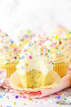 two cupcakes with white frosting and sprinkles on a pink napkin