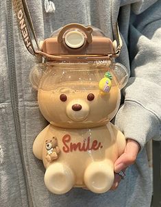 a person is holding a small teddy bear in a jar with the word smile on it