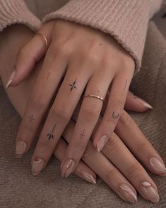 a woman's hands with tattoos on their fingers