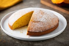 a cake on a plate with one slice cut out and powdered sugar on top