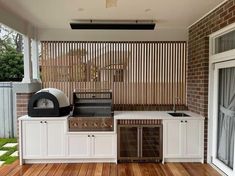 an outdoor kitchen with wood flooring and white cabinetry on the outside side of the house