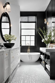 a white bath tub sitting next to a large window in a bathroom with black walls