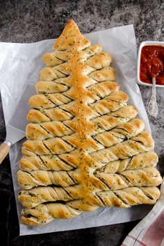 a christmas tree shaped pastry sitting on top of a piece of wax paper next to a bowl of ketchup