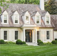 a white house with black shutters on the front and side windows, grass in front