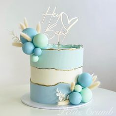 there is a blue and white cake with feathers on the top that says happy birthday