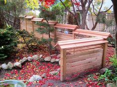 a wooden bench sitting in the middle of a garden with red leaves on the ground