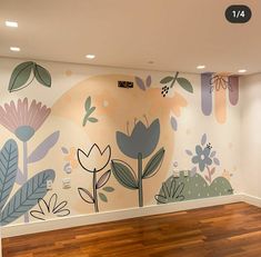 an empty room with flowers painted on the wall and wood flooring in front of it