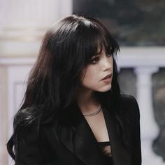 a woman with long black hair wearing a black suit and choker on her neck