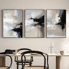 two black and white paintings hanging above a dining room table