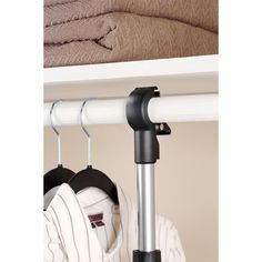 an ironing board is hanging on the wall next to some shirts and sweaters