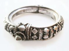 A beautiful Indian petite silver bracelet with lovely applique decoration on almost all of the body of the bracelet. It is hinged and closes with a central screw clasp. The patina on this high-grade silver bracelet is lovely and in good condition for its age. It is meant for quite a small wrist. The hinge is wobbly. Inner circumference is 13.5 cm (5 3/8"). Inner diameter is 4.7 cm (1 7/8"). Width is 1 cm (just under 1/2"). Weight is 59.5 grams. For more Indian jewelry: https://www.etsy.com/shop/ Silver Hinged Bracelets For Weddings, Ornate Hinged Bangle Bracelets, Traditional Hinged Bracelet Jewelry, Silver Hinged Bracelet For Wedding, Ornate Hinged Bangle Bracelet, Vintage Bangle Bracelet With Sterling Silver Clasp, Hinged Sterling Silver Bangle Bracelet As Gift, Hinged Sterling Silver Bangle Bracelet For Gift, Classic Silver Ceremonial Bangle