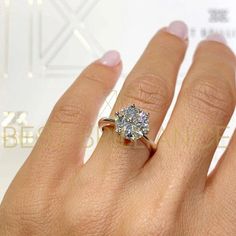 a woman's hand with a diamond ring on top of her finger and the other hand holding an engagement ring