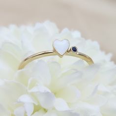 a close up of a flower with a heart ring on it's side and a blue stone in the middle