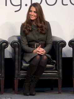 a woman sitting in a black chair with her legs crossed and wearing high heeled boots