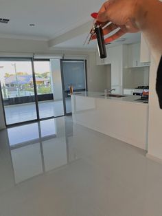 a person holding a remote control in their hand near a kitchen and living room with sliding glass doors