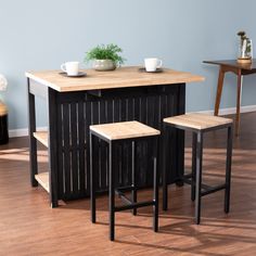 a kitchen island with three stools in front of it and two cups on top