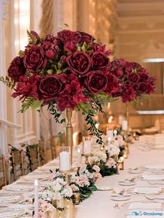 a long table with flowers and candles on it in a fancy room at a wedding