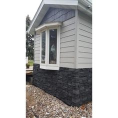 a house that has some rocks on the ground in front of it and a window