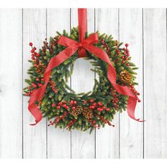 a christmas wreath hanging on the side of a wooden wall with red ribbon and pine cones