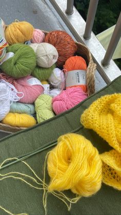 several balls of yarn are in a basket next to some skeins of yarn