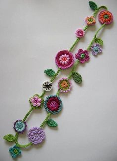 crocheted flowers and leaves are arranged on a white surface with green stems in the center