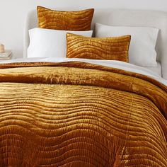 the bed is made up with gold comforters and pillows