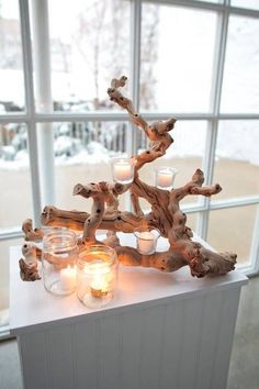 a candle holder made out of driftwood with candles in it on a window sill