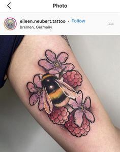 a woman's thigh with a bee and flowers tattoo on her leg, next to a pink flower