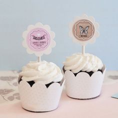 two cupcakes sitting on top of a table next to each other with paper decorations