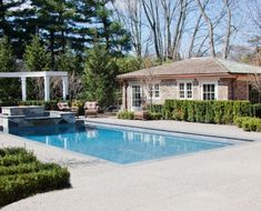 an outdoor swimming pool surrounded by hedges and trees