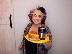 a woman holding a plate with some food on it and a cup in her hand