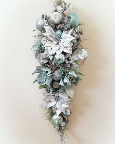 a christmas wreath hanging on the wall with ornaments and greenery around it's edges