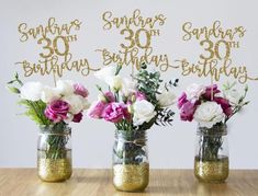 three mason jars with flowers in them on a table