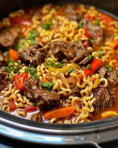 a bowl filled with noodles, beef and vegetables