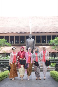 four women are standing in front of a statue with pink scarves on their heads