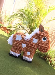 a fake horse made out of toilet paper on the grass in front of a building