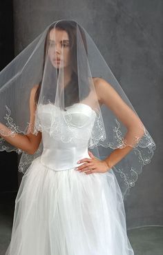 a woman wearing a white wedding dress with a veil on her head and hands on her hips