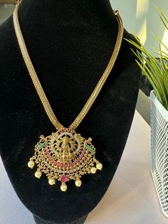 ⛓️ Simple temple antique finish  necklace  with beautiful matching earrings is perfect for any traditional look. ⛓️The green & ruby & white  stones with Lakshmi ji  in the  center pendant adds  a extra Ethnic touch to the necklace  ⛓️Not sold separately only with clothing purchase as a combo offer . ⛓️No returns or exchanges. Luxury Women's Temple Jewelry Necklace, Luxury Heavy Temple Necklace For Puja, Luxury Traditional Temple Necklace, Luxury Hallmarked Temple Necklace For Festivities, Luxury Temple Jewelry Necklace, Luxury Hallmarked Temple Necklace For Anniversary, Luxury Antique Temple Necklace For Ceremonial Occasions, Luxury Round Temple Necklace As Gift, Luxury Antique Temple Necklace For Gift