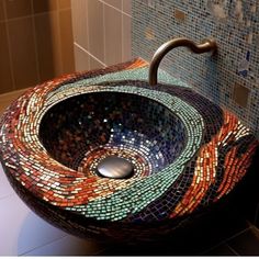 a sink made out of mosaic tiles in a bathroom with a metal faucet