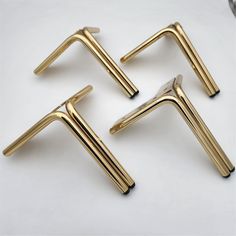 four gold metal handles on a white surface