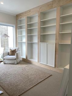 an empty living room with white bookcases and beige carpet