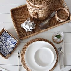 the table is set with plates, utensils and a basket