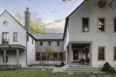 two large white houses sitting next to each other on top of a lush green field