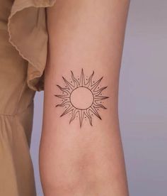 a woman's arm with a small sun tattoo on the left side of her arm