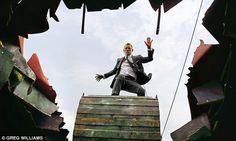 a man standing on top of a wooden structure with his hands up in the air